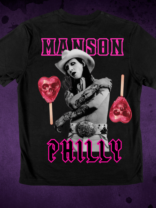 Black t-shirt with a bold gothic western theme featuring a monochrome figure in a cowboy hat, pink skull lollipops, and the words "Manson Philly" in hot pink Old English-style font